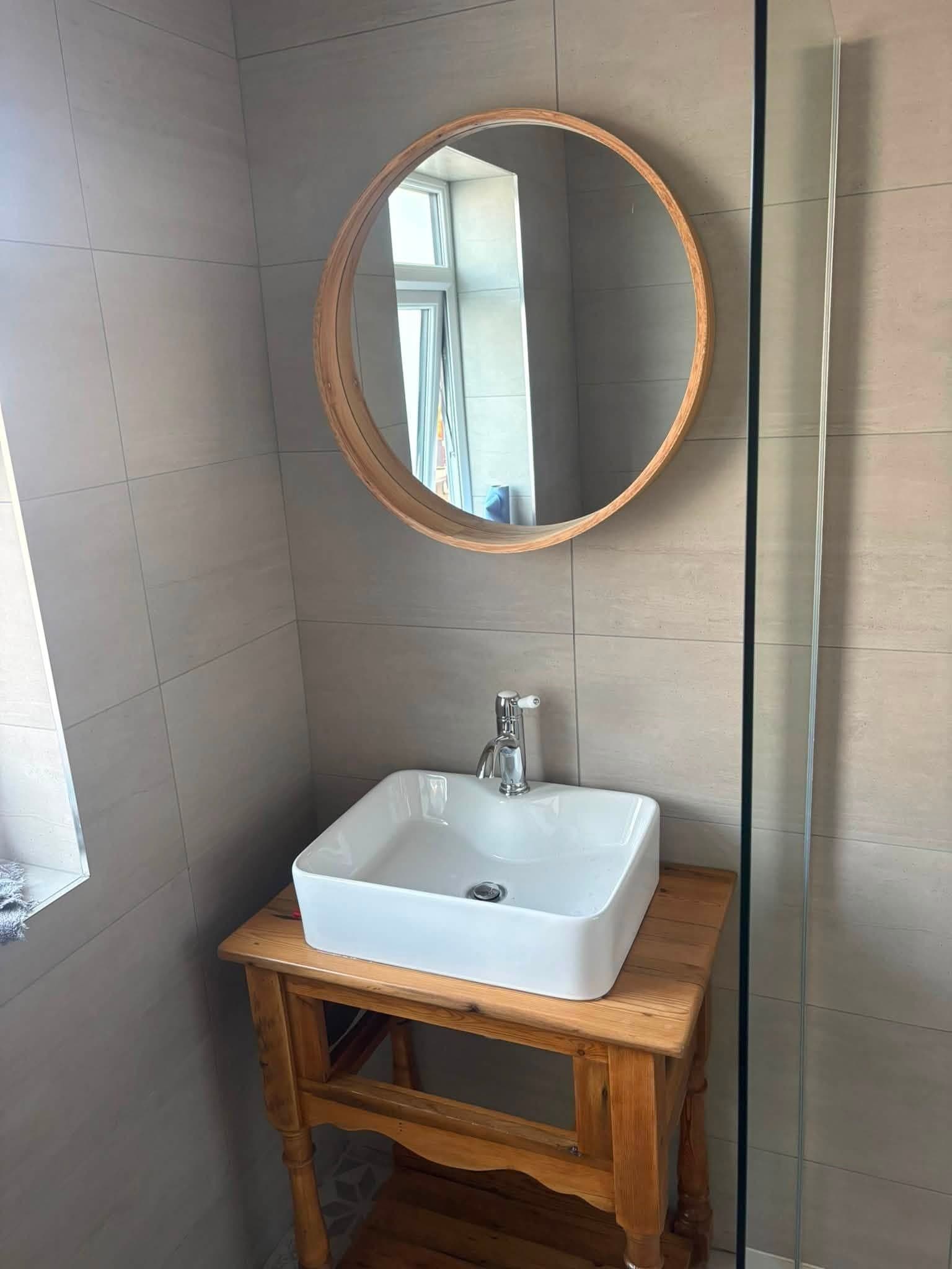 Finished basin on a wooden washstand under a round mirror