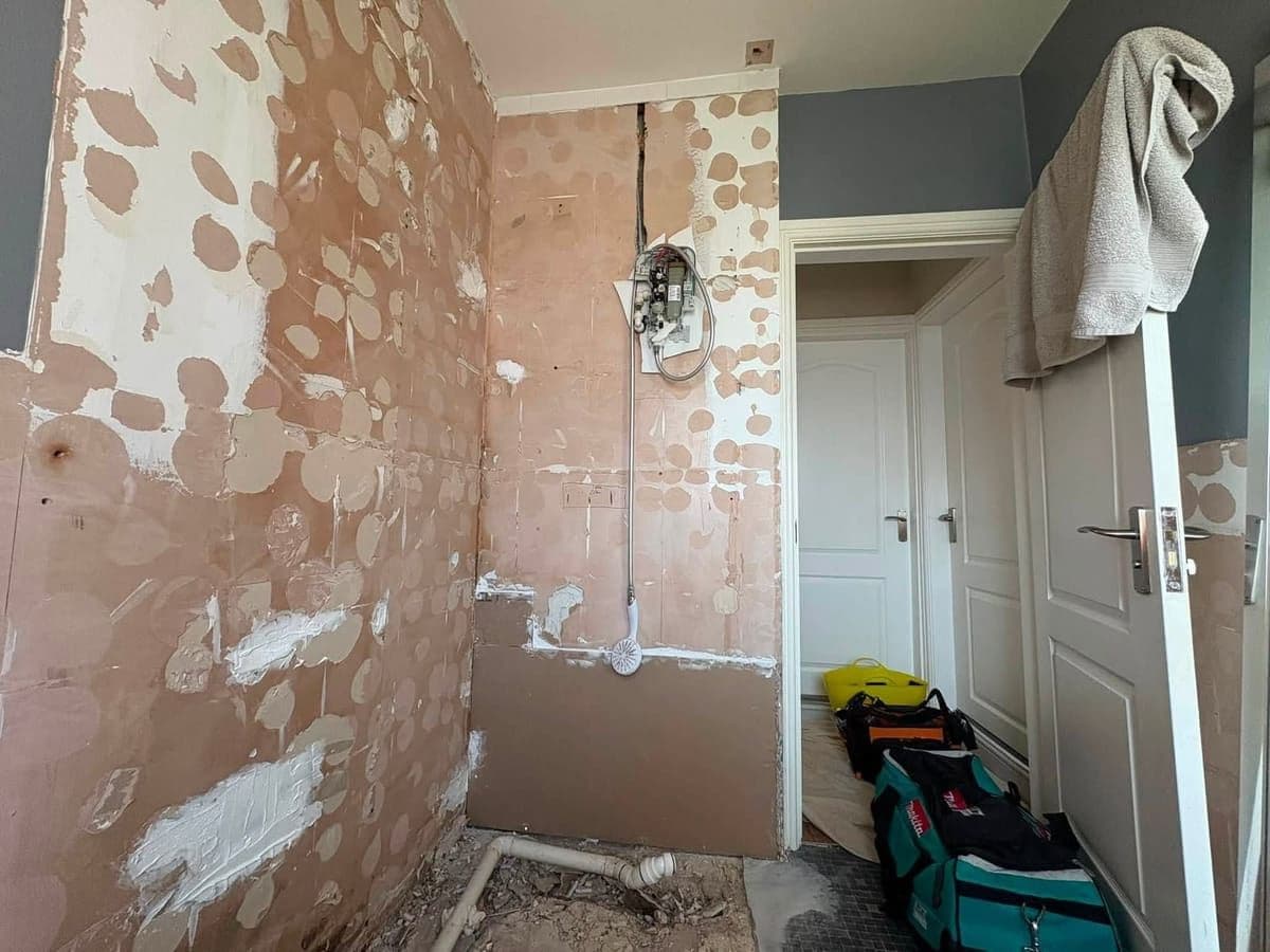 Bare plaster walls with new shower pipework chased in